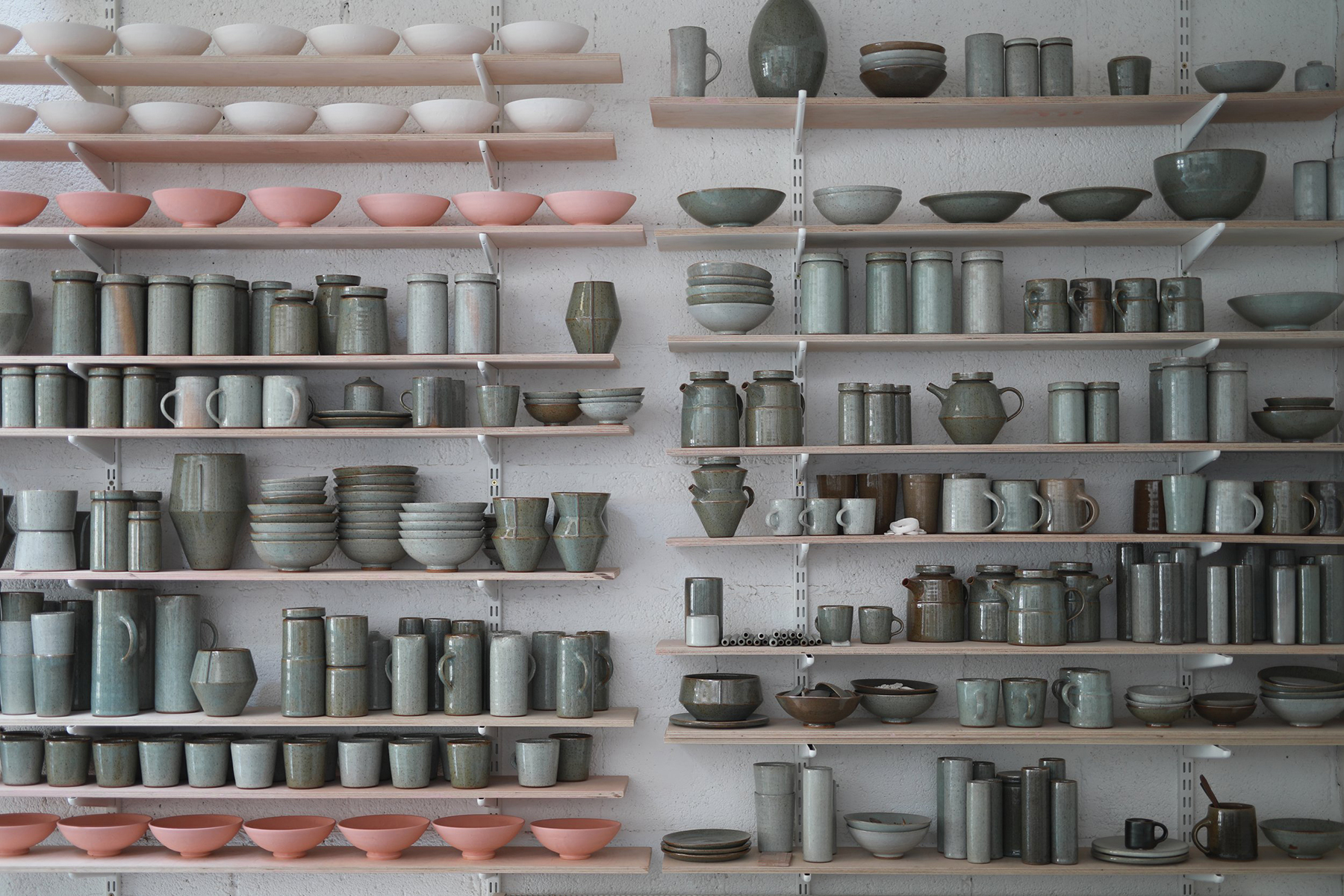 Multiple shelves of glazed ceramic pieces.